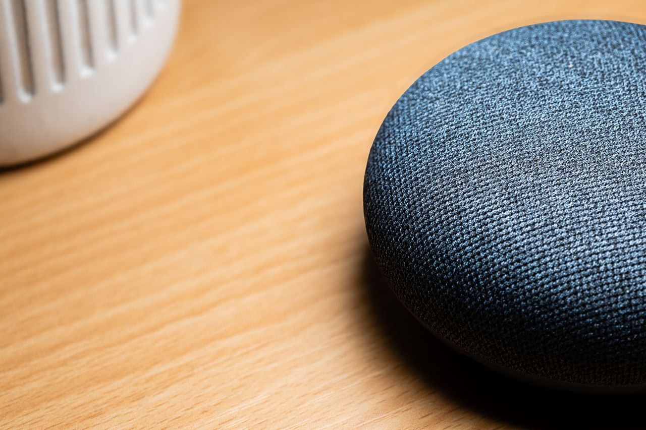 services-04 A close-up view of a smart speaker on a wooden table, capturing texture details.